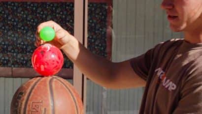 boy holding a stack of balls of all different sizes