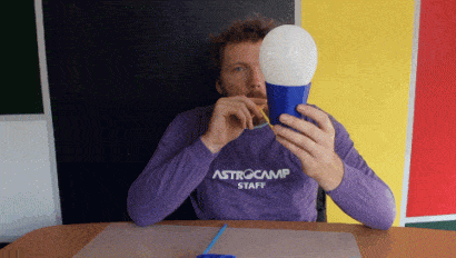 man blowing air into cup to demonstrate bernoulli's principle