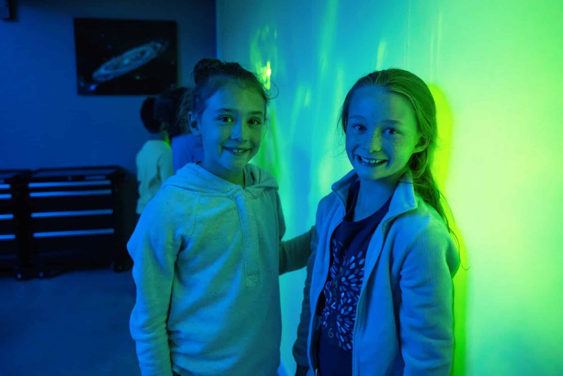 Two girls smiling in blue and green.