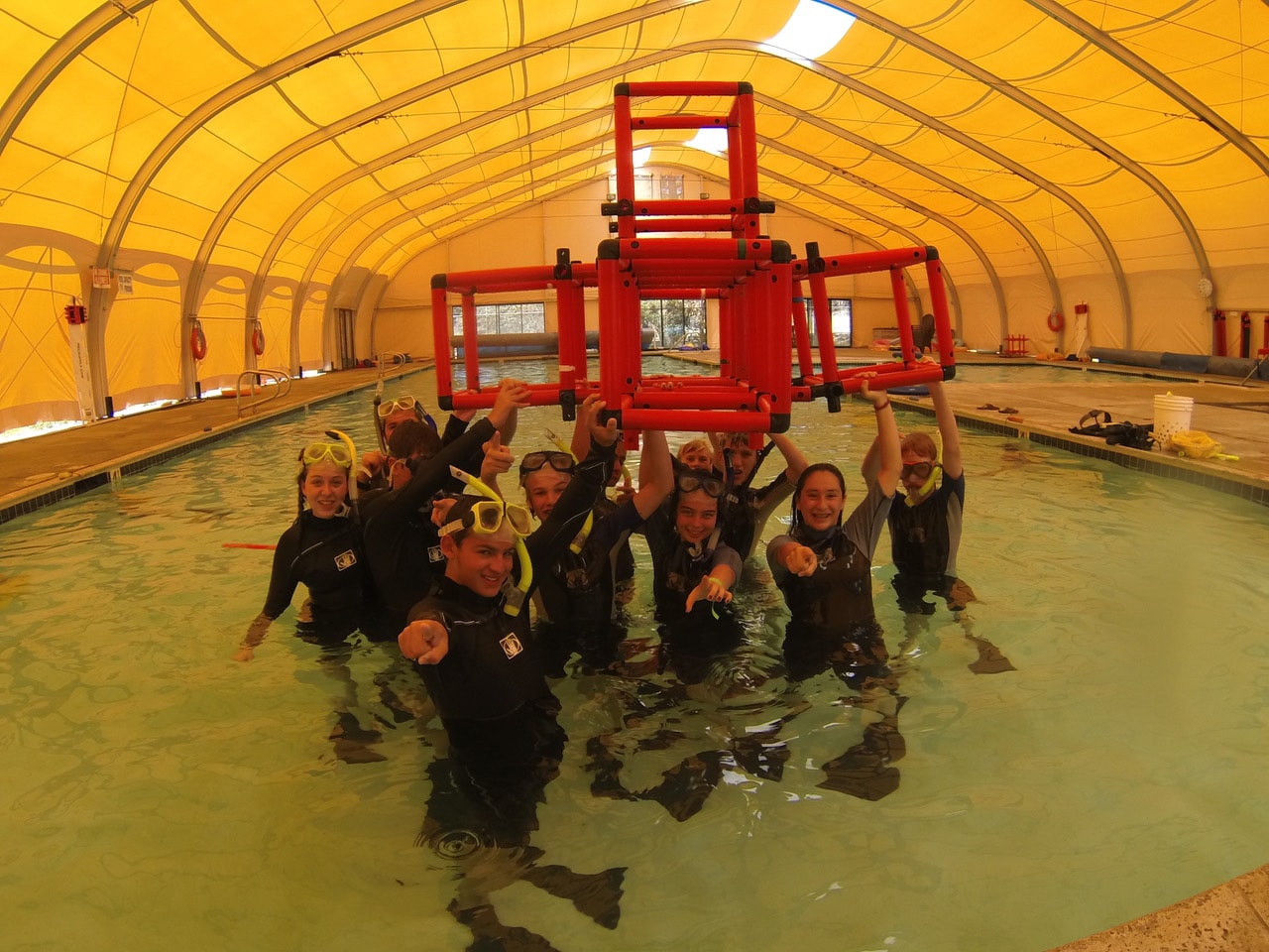Kids pointing in snorkeling gear in pool.