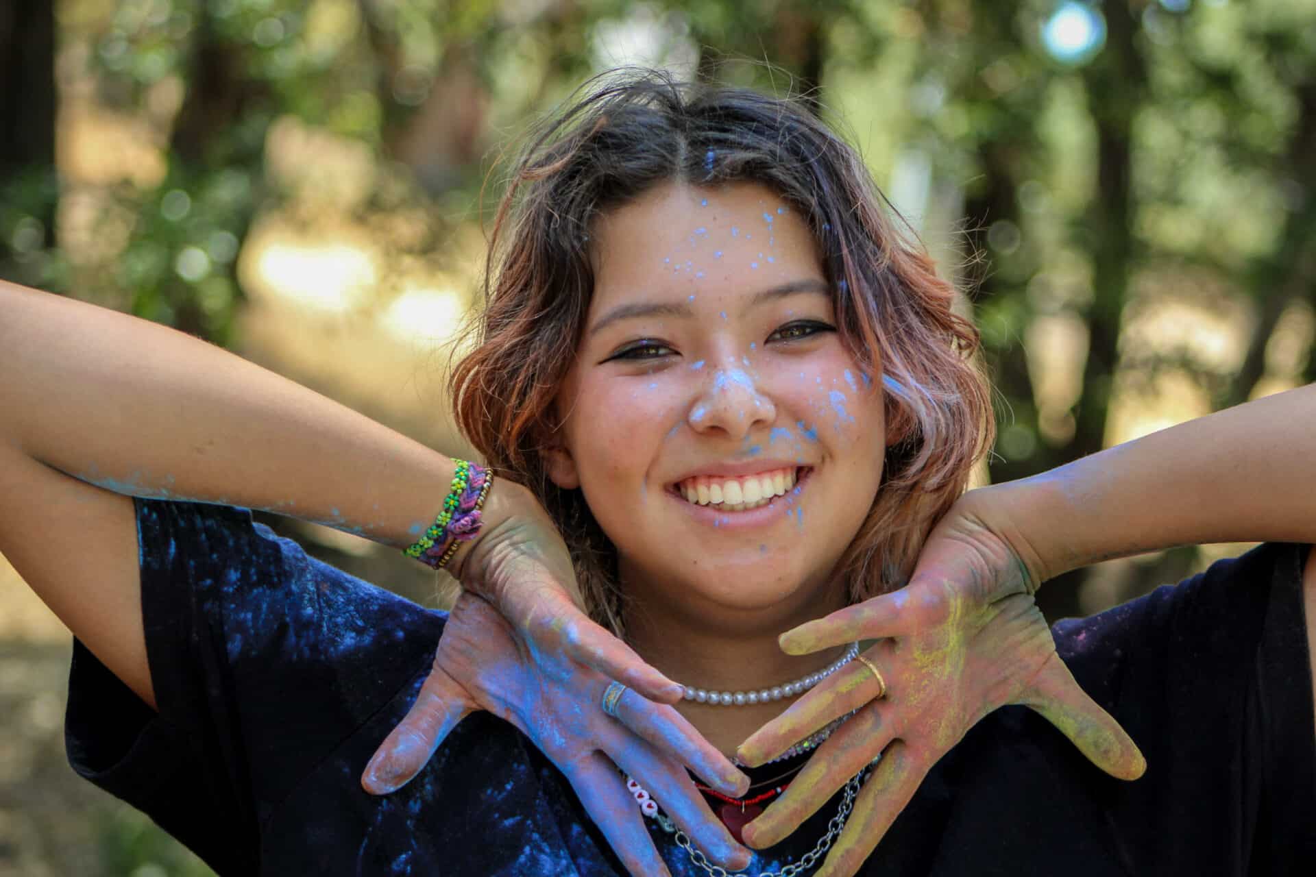 Girl with paint on her hands smiling.