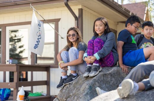 Girls sitting on rock smiling.