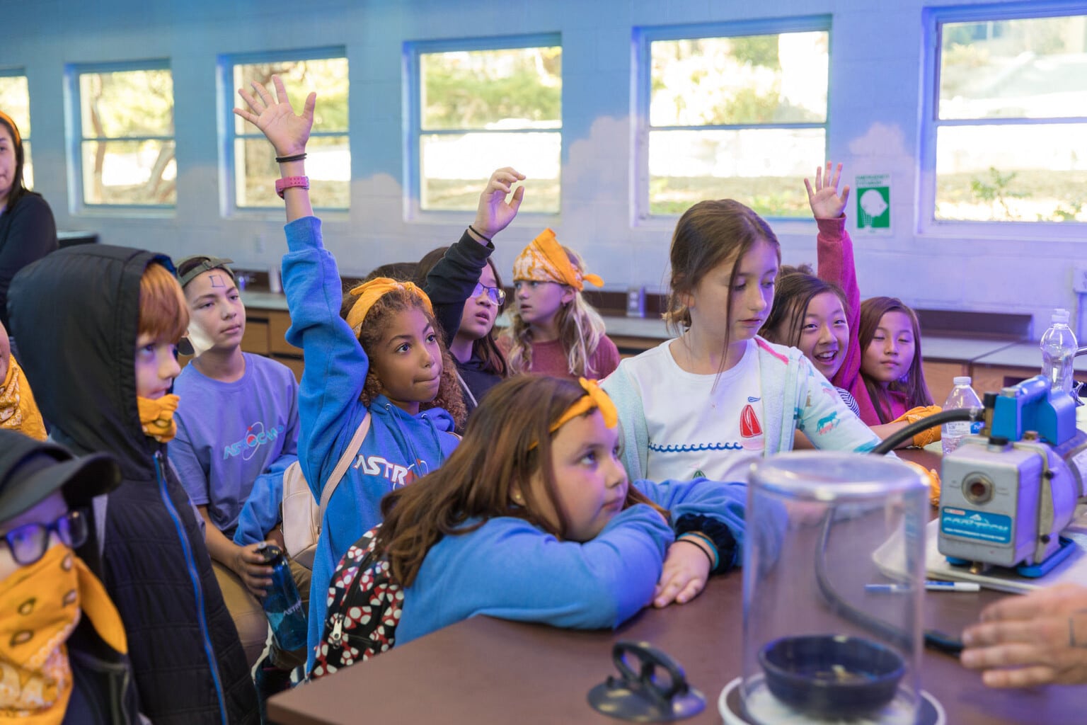 Kids in classroom raising hands.