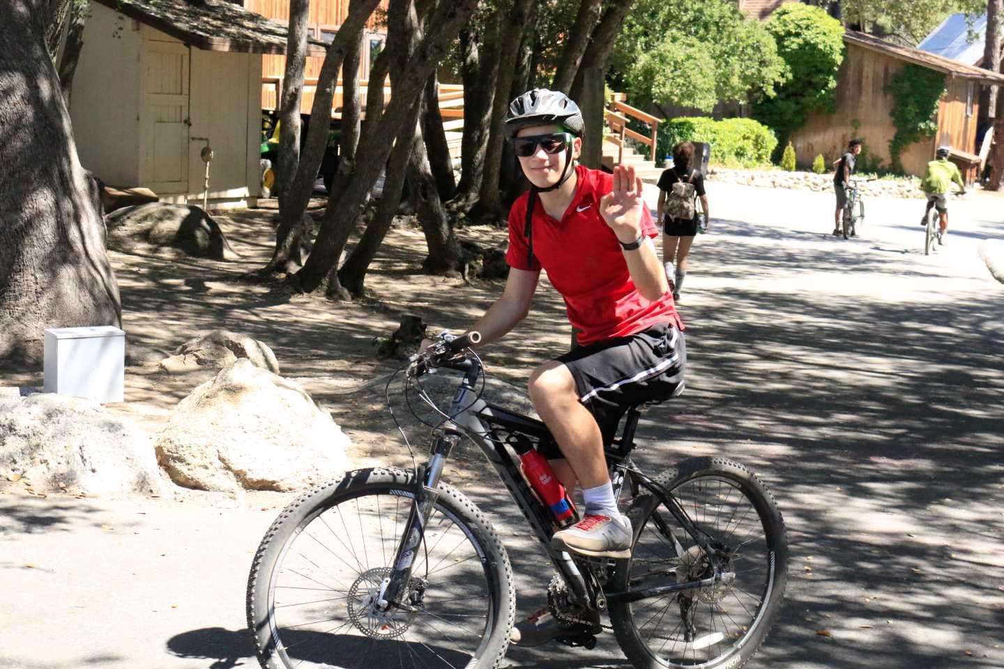 Boy waving riding a bike.