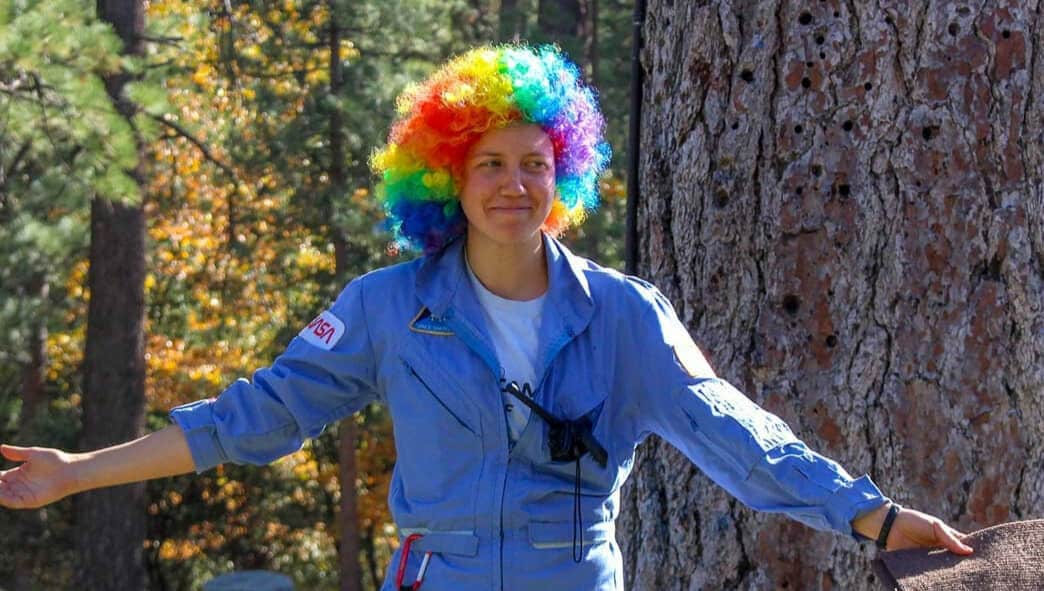 Person in blue jumpsuit and clown hair.