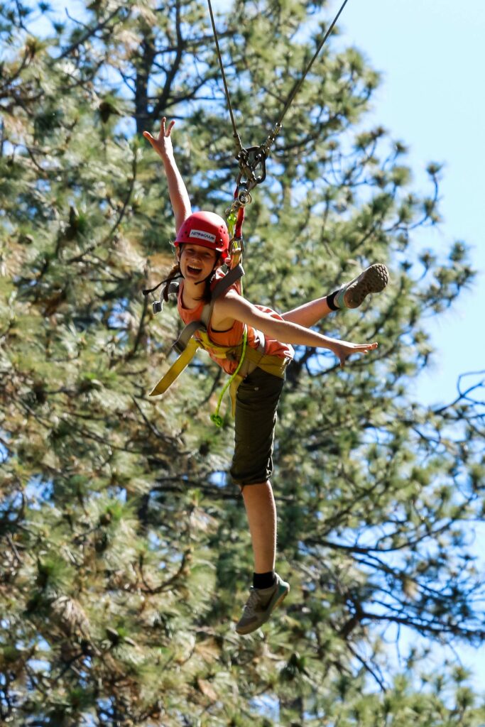 Girl ziplining during a summer camp outdoor activity