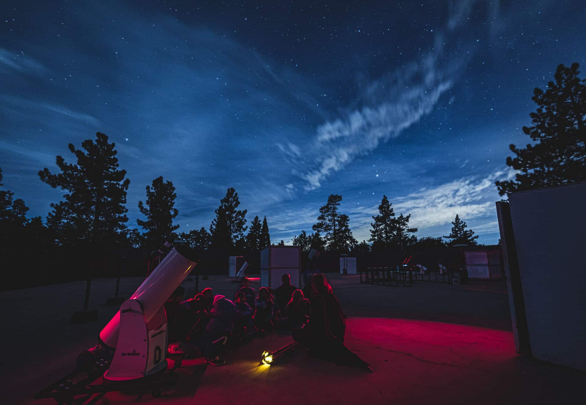 Kids sitting around telescope.