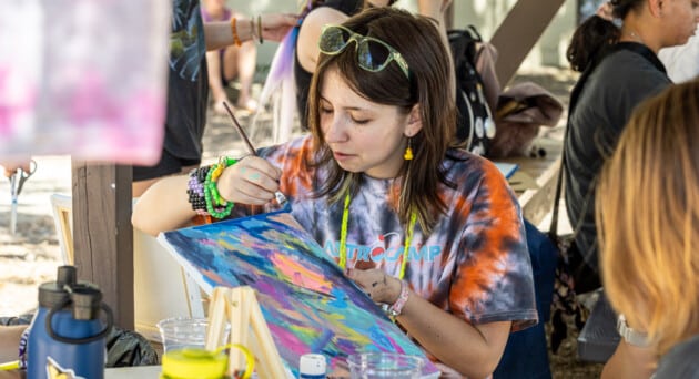 Camper focused on painting activity, exploring creativity at camp.