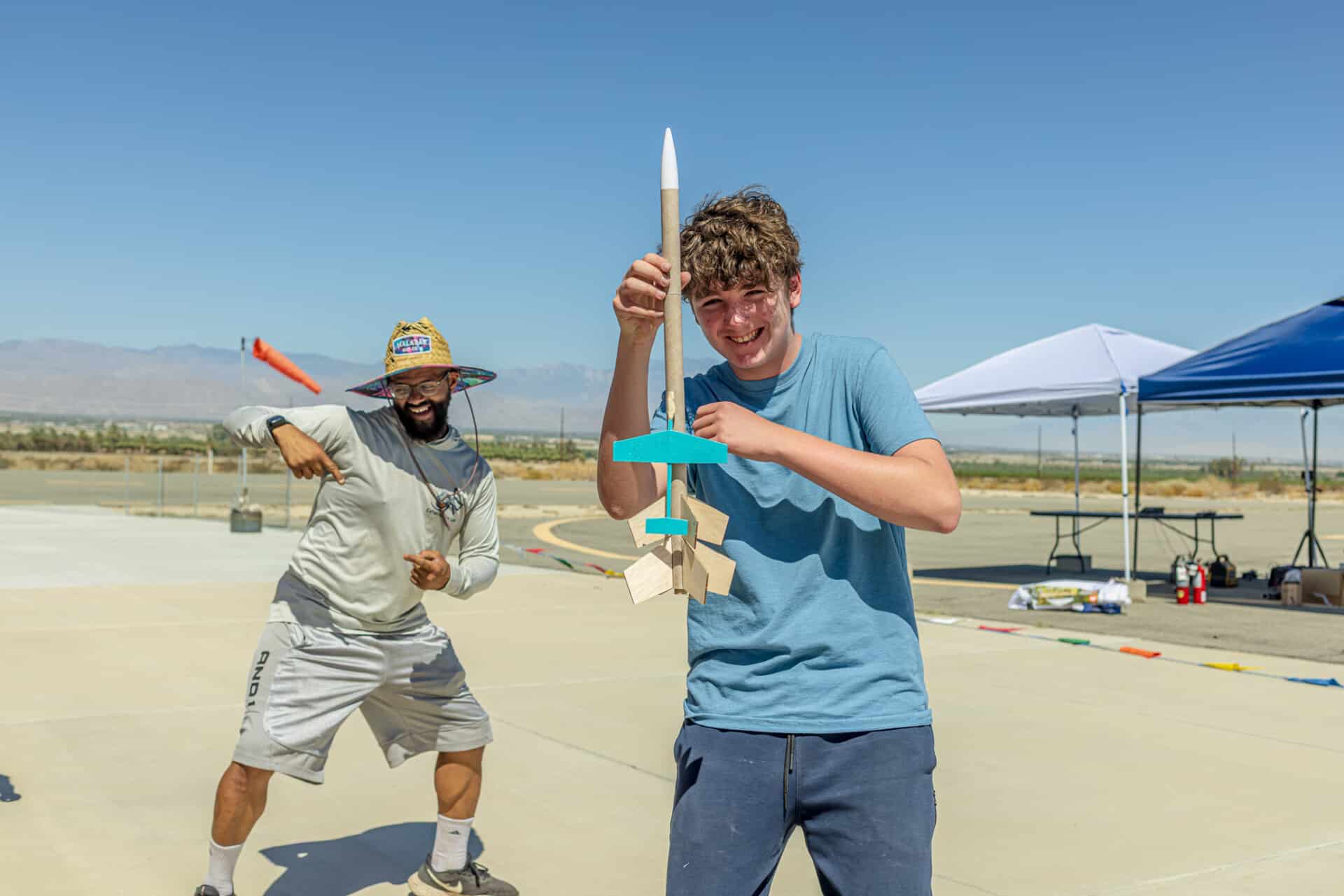 Smiling camper holding their finished rocket, celebrating a successful project.