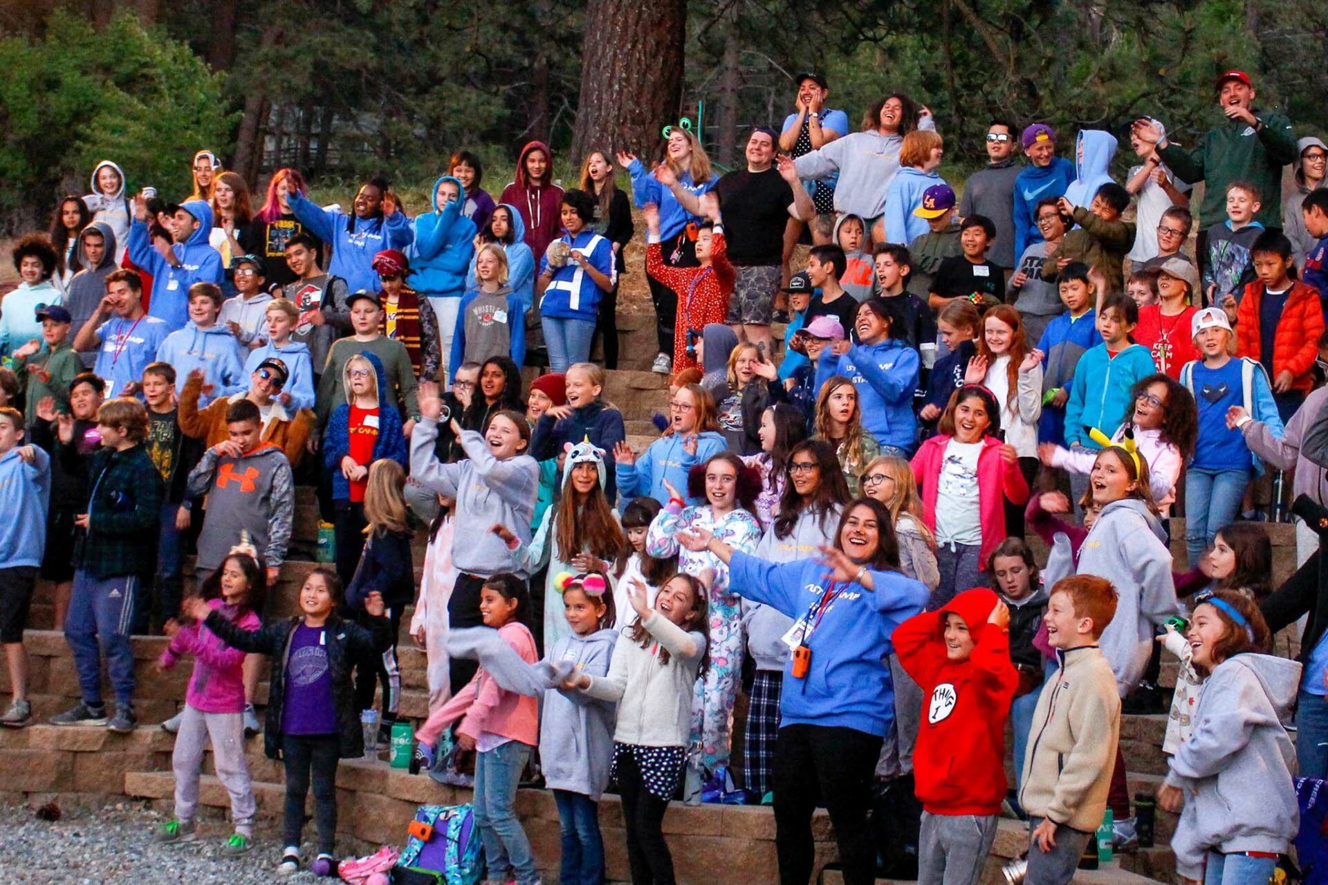 Kids standing outdoors on bleachers.