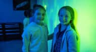 Two girls smiling in blue and green.