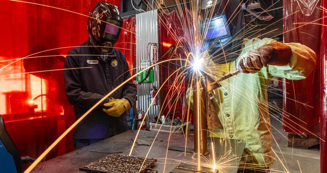 Individual camper practicing welding technique with sparks flying in a supervised activity