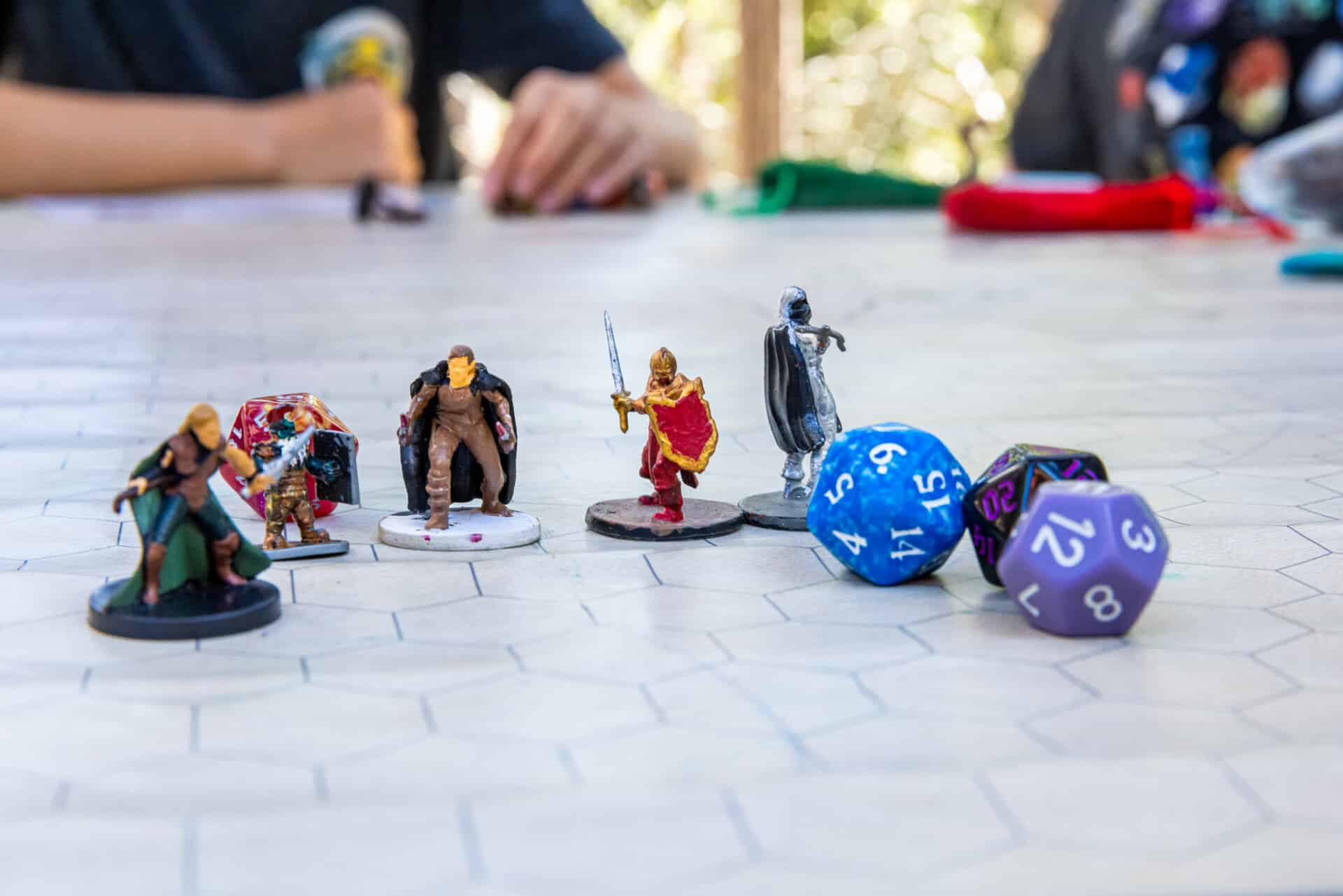 Close-up of Dungeons & Dragons dice and character figures during tabletop role-playing game at summer camp.