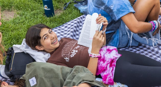 Camper smiling and reading during afternoon rec time at AstroCamp’s Southern California sleepaway camp.