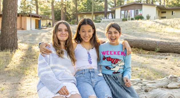 Group of girls smiling outside their cabin at AstroCamp in the San Jacinto Mountains.